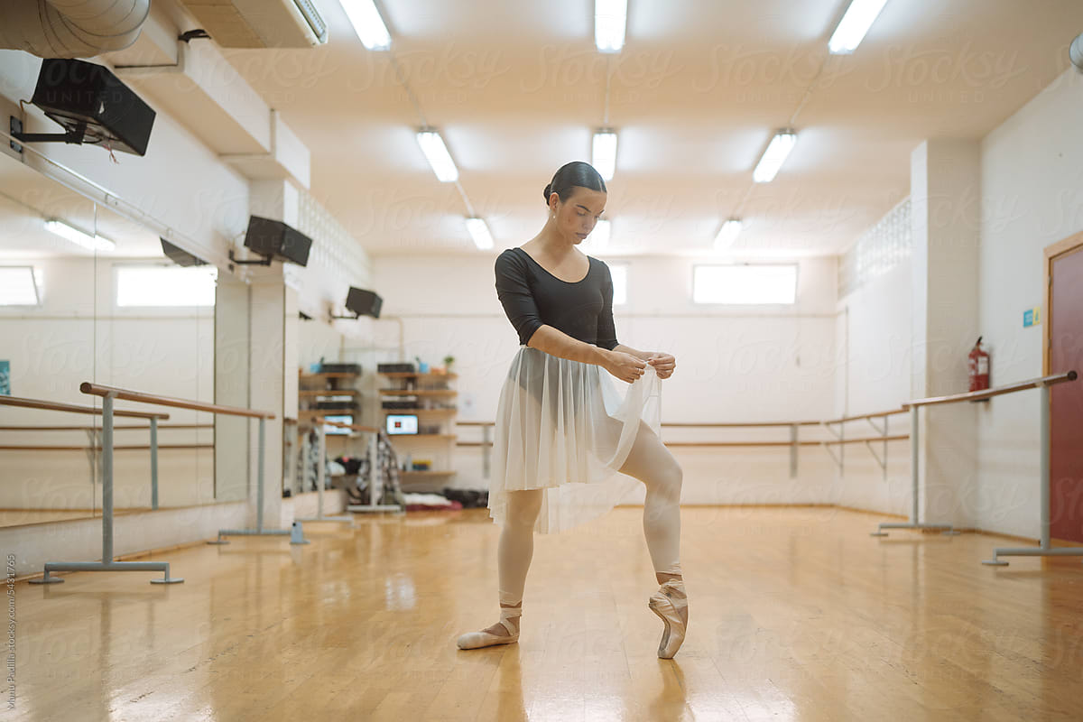 Young woman dancer practicing ballet in light studio