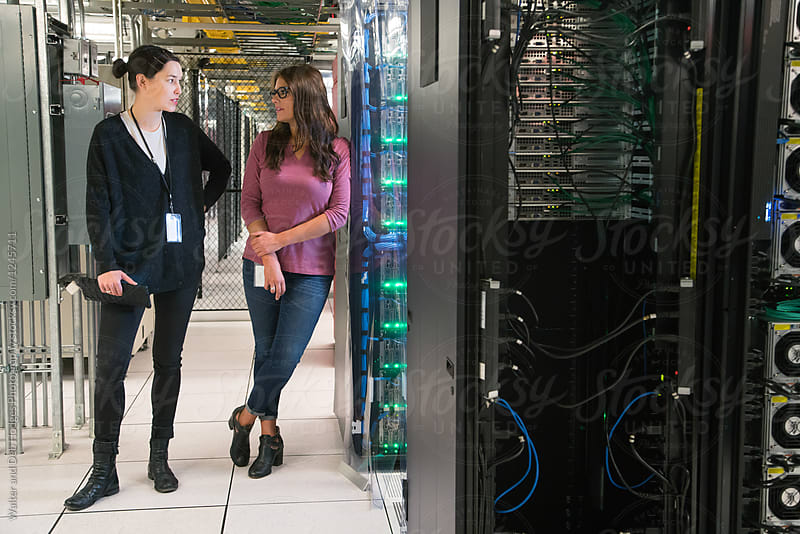 Two women in server room talking to one another