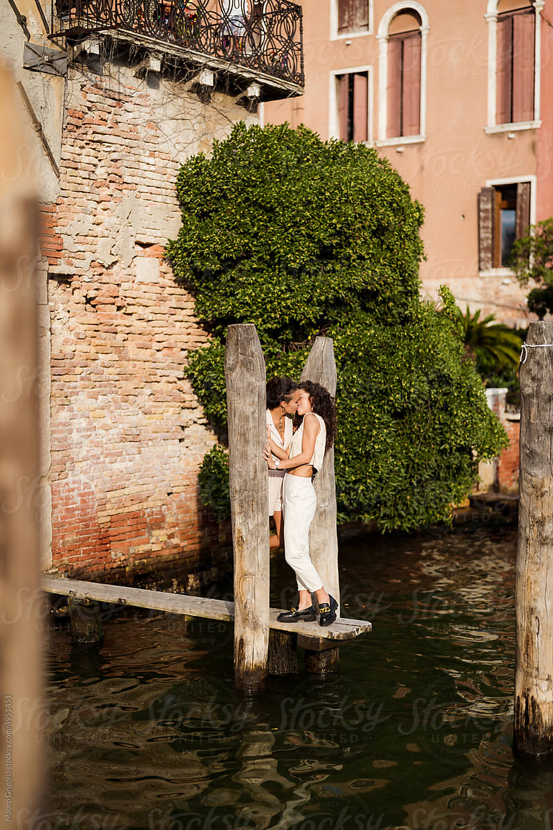 Female couple kissing along a river in Venice