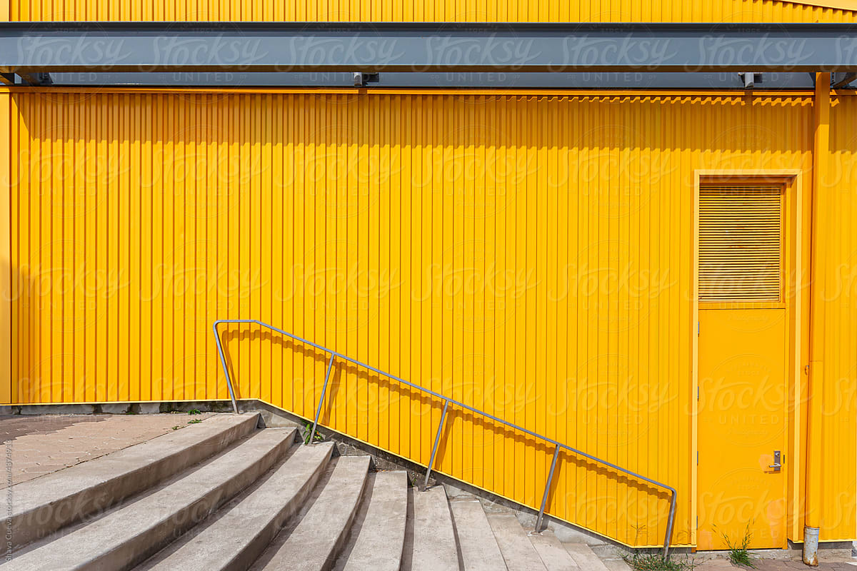 yellow wall in front of stairs with railing