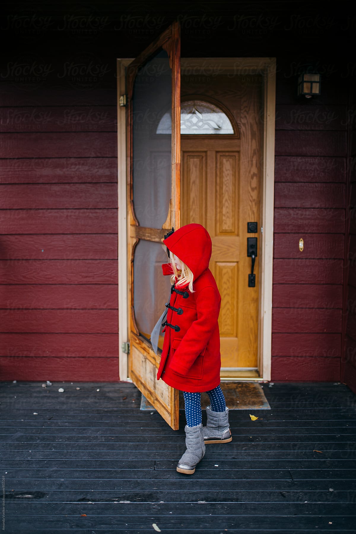 Side View of A Young Girl in A Red Coat Opening her Front Door