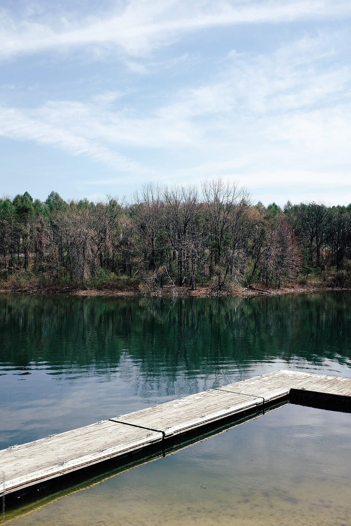 Landscape view of a floating dock in a clear lake with trees and mountains in the background