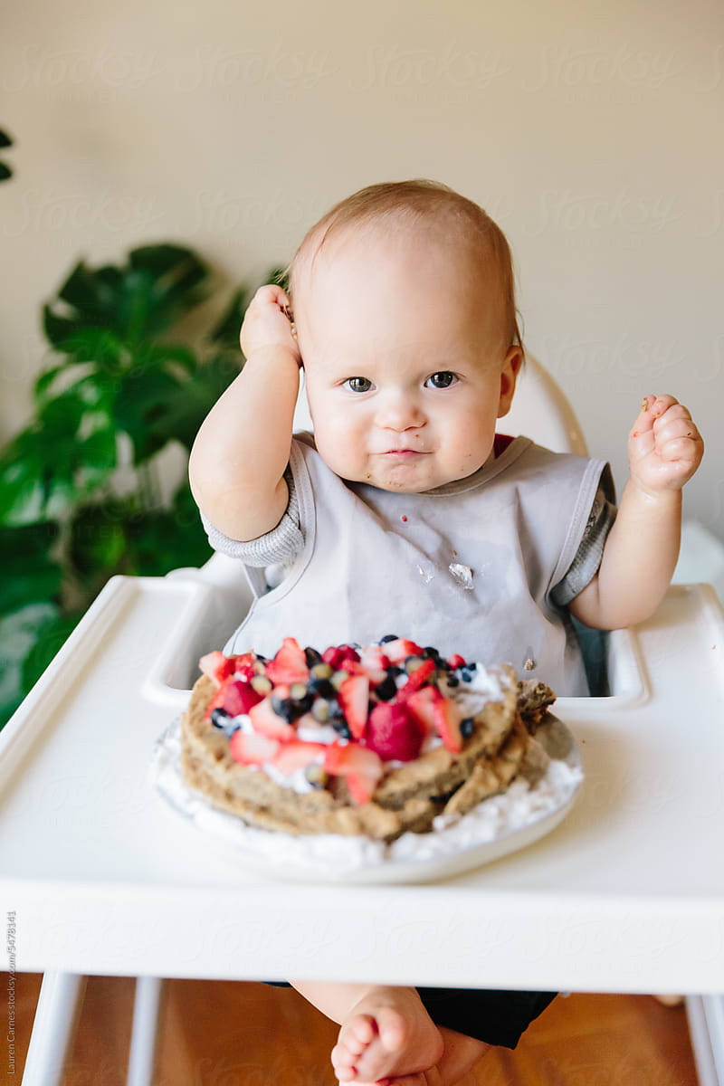 Baby eating fruit smash cake on first birthday