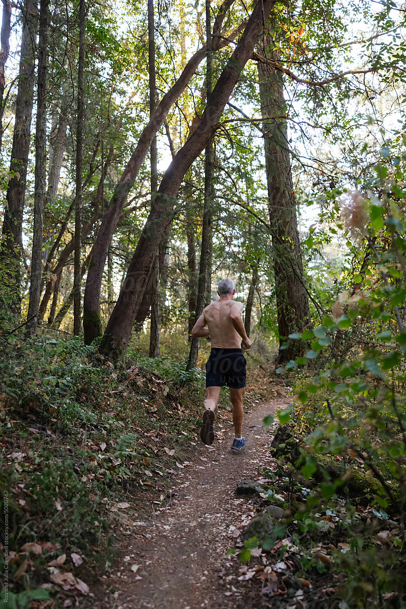 Man training and running on trails in the forest.