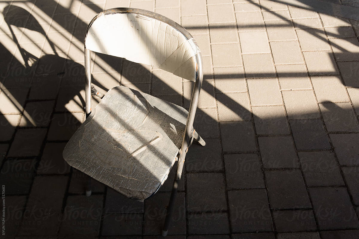 White chair with its shadow on the street