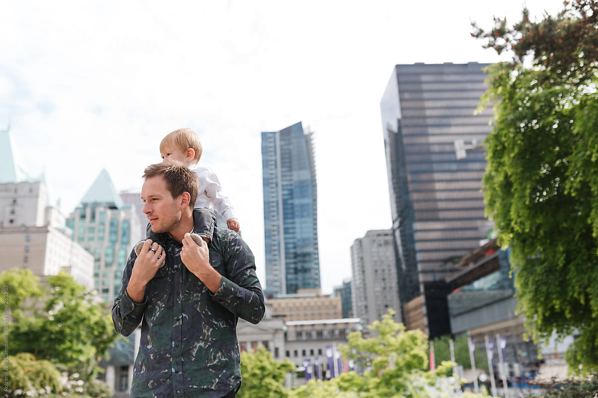 Young, cool dad holding son on his shoulders in the city