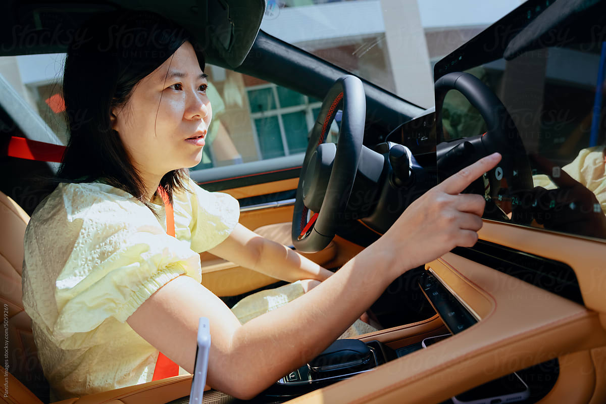 woman driver touches control screen in modern electric car