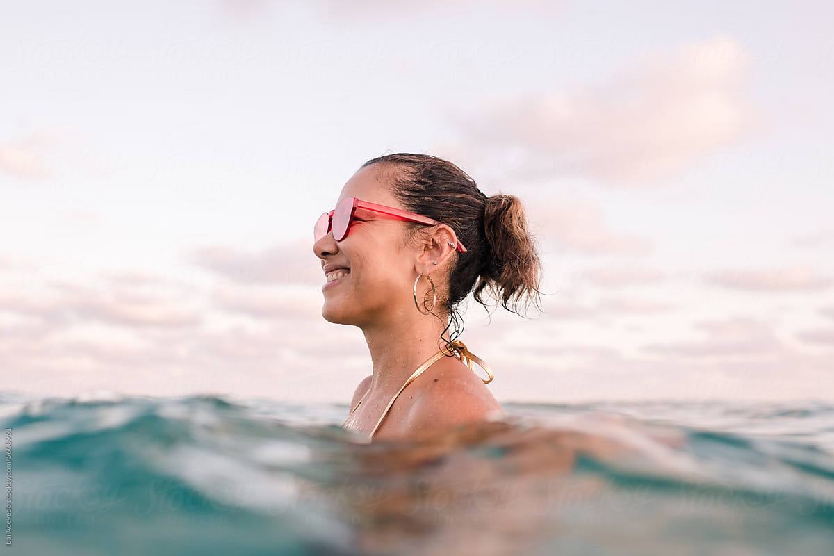 Smiling woman standing in the sea with red sunglasses