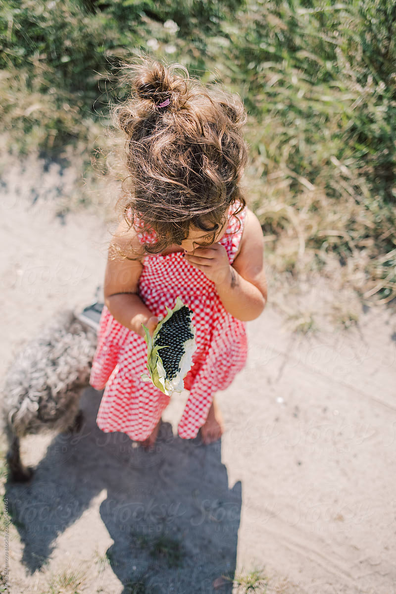 Curly-Haired Girl Enjoying Sunflower Seeds outside
