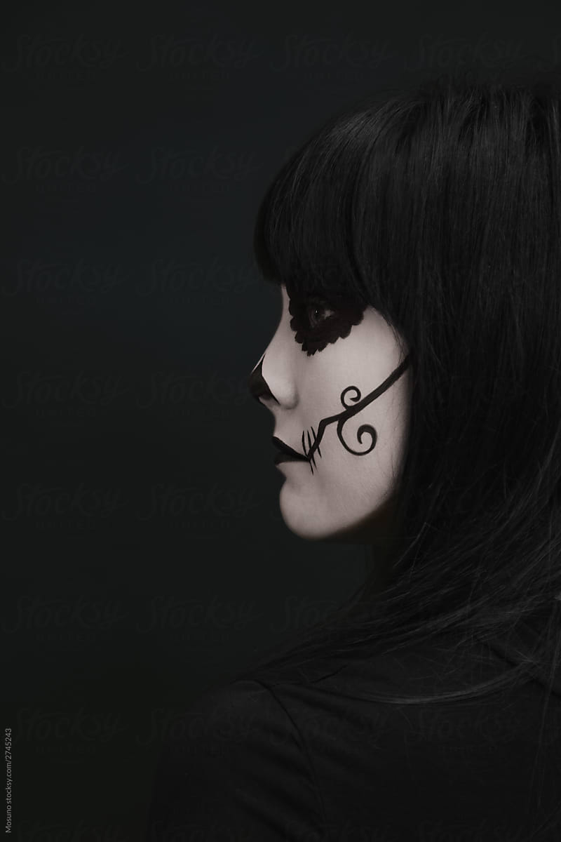 Elegant woman in Halloween black dress with skull makeup