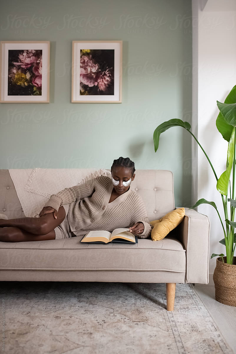 Female bookworm reading book on sofa