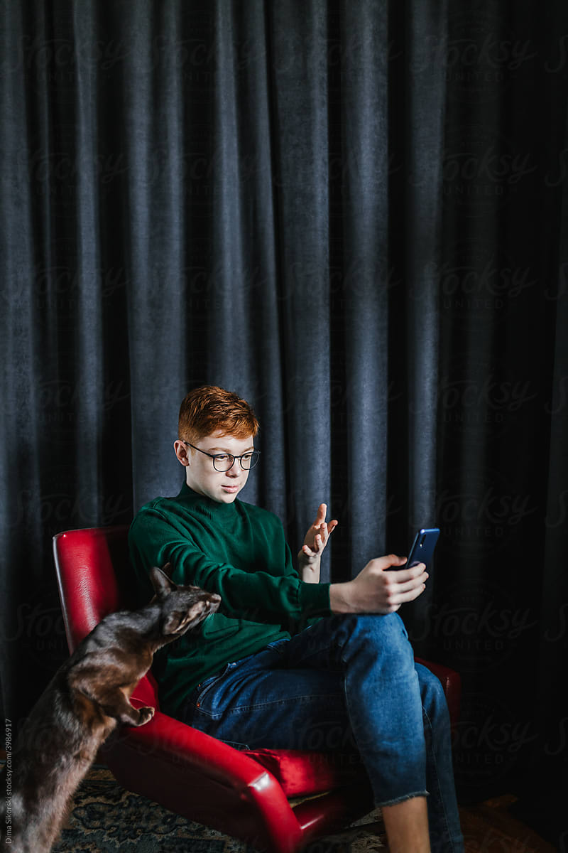 a red-haired teenager with a smartphone and a pet
