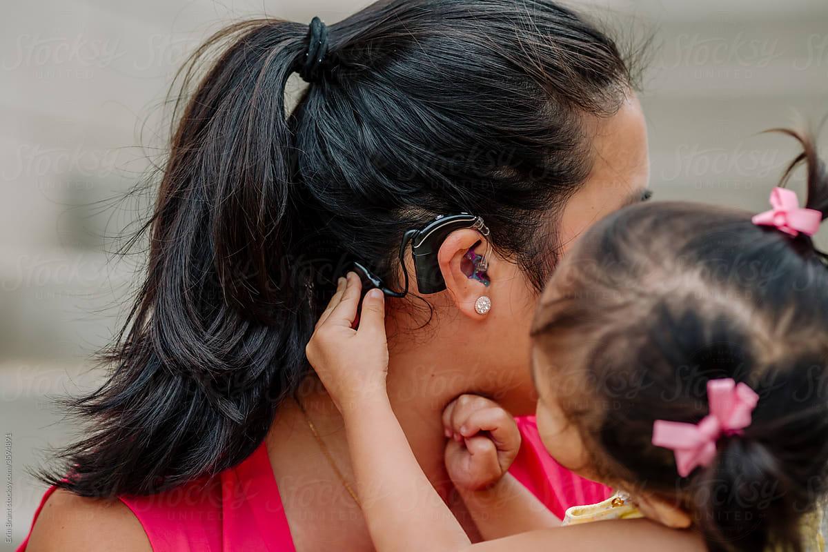 2 year old child examines her mother\'s cochlear implant