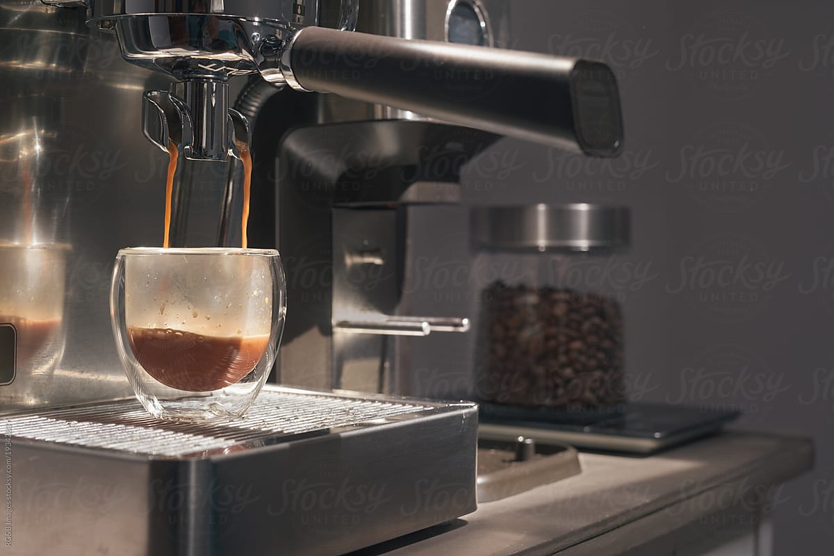 Freshly brewed espresso pouring in a glass cup