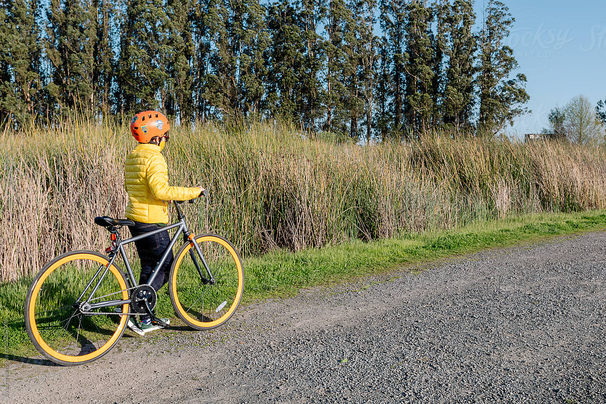 Teen boy walking with bike along road in countryside