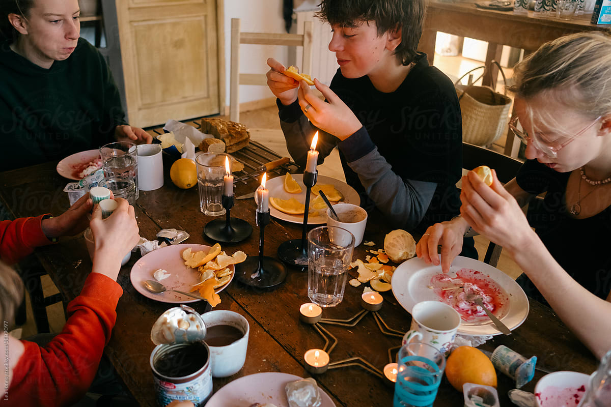 teen boy eating orange during family breakfast/brunch