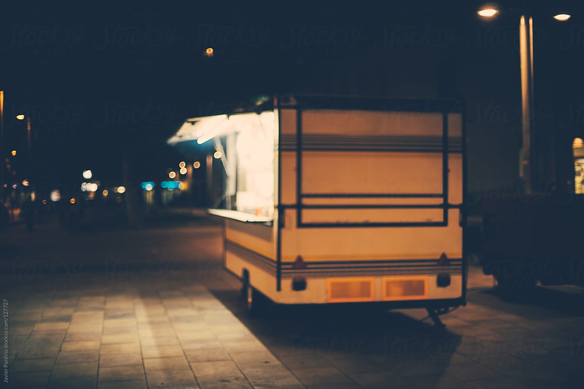 Food truck parked on the sidewalk at night.