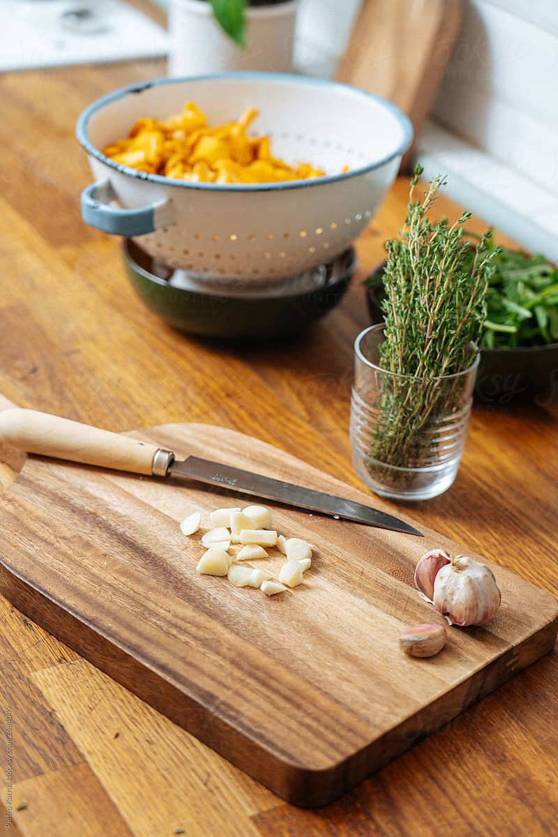 Cutting board with chopped garlic and thyme in glass
