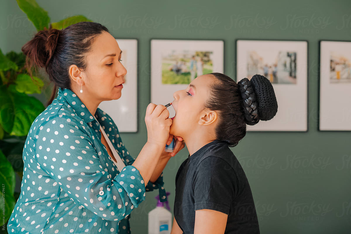 Mother applying makeup to her daughter for a Mexican performance act