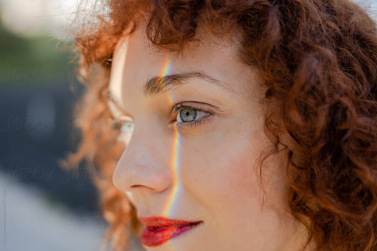 Portrait of fair red haired woman with rainbow streak on face