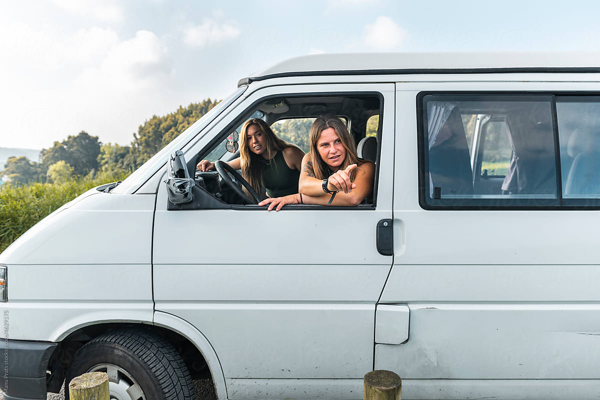 Millennial women driving camper van during surf trip
