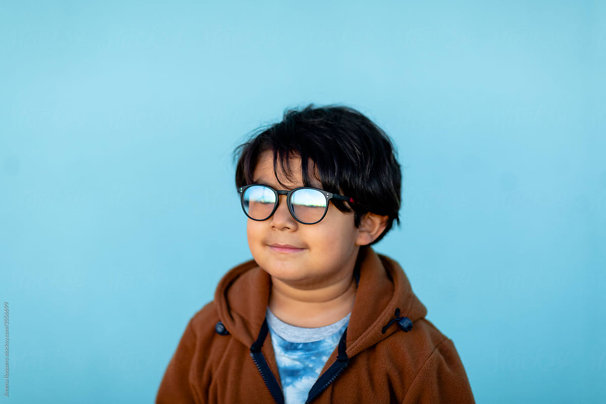 Portrait of 6-year old hispanic kid with glasses  over blue background