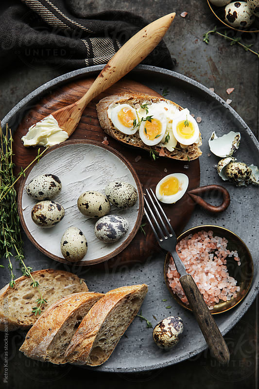 Quail eggs, pink salt, thyme, and quail egg sandwich on dark metal background