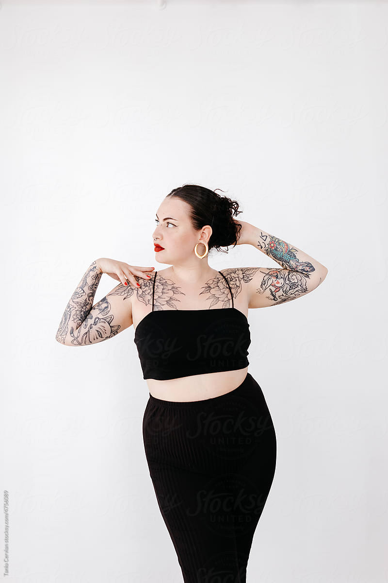 Dreamy plus size tattooed woman in studio