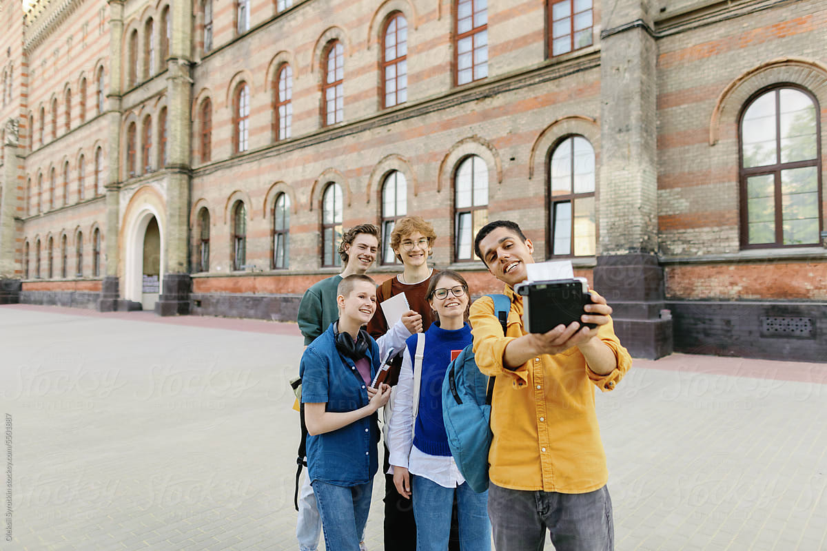 Taking selfie collegue freshmans fun together. Campus pedestrian zone