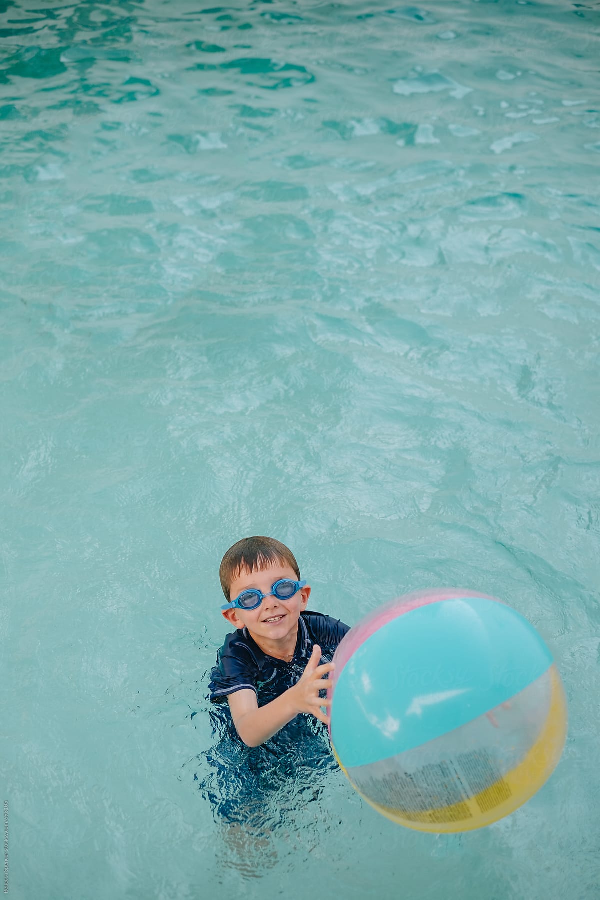 Happy boy with ball in swimming pool