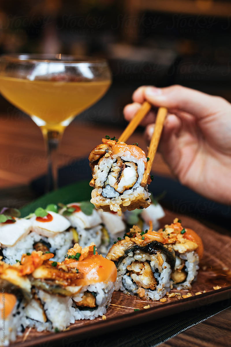 Sushi Rolls being Held By ChopSticks