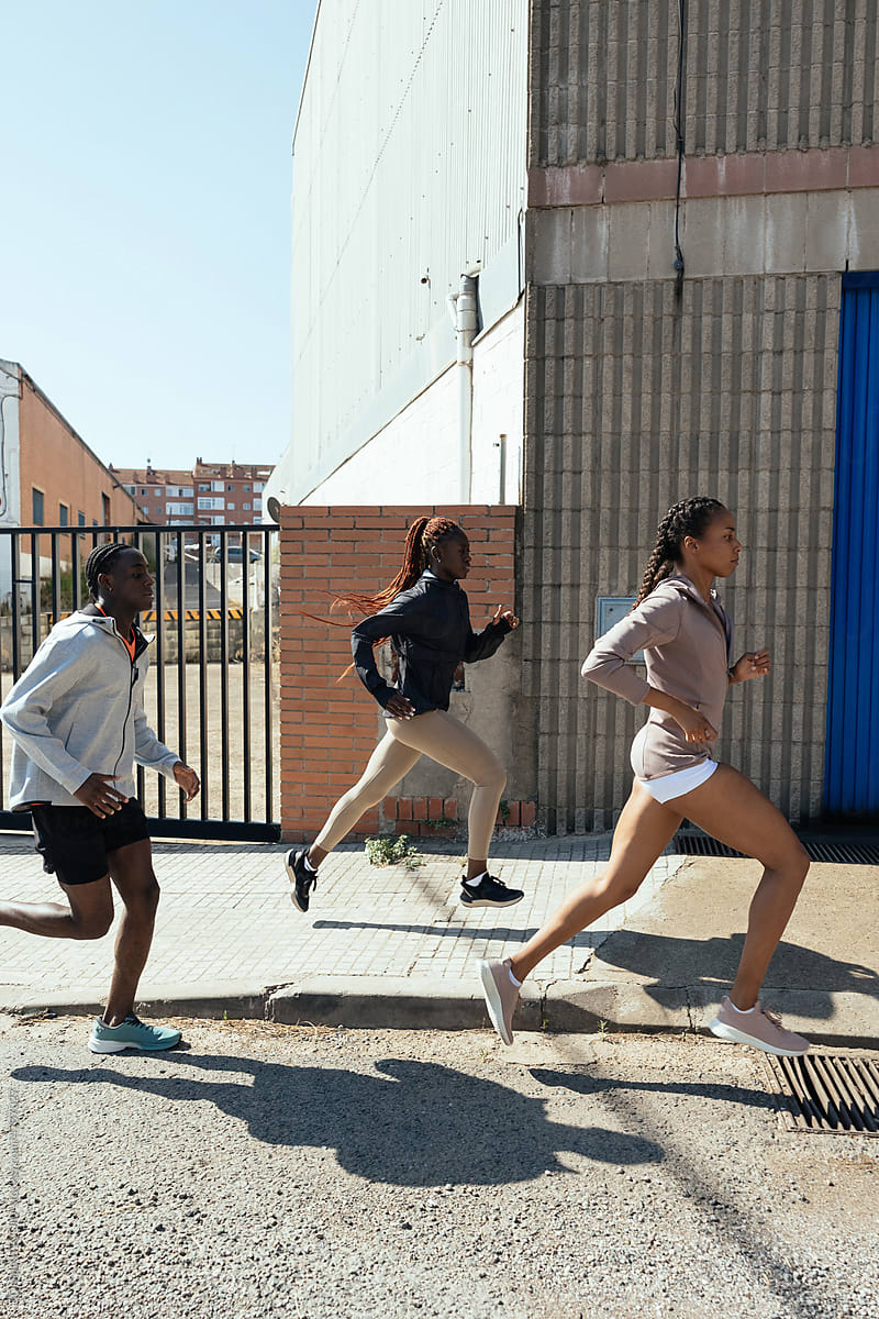 African American athletes running on sunlit street