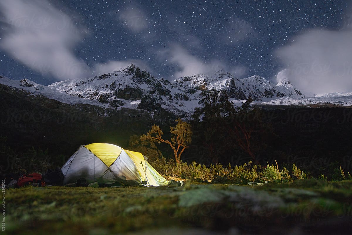 Lit camping tent under the night sky in the mountains