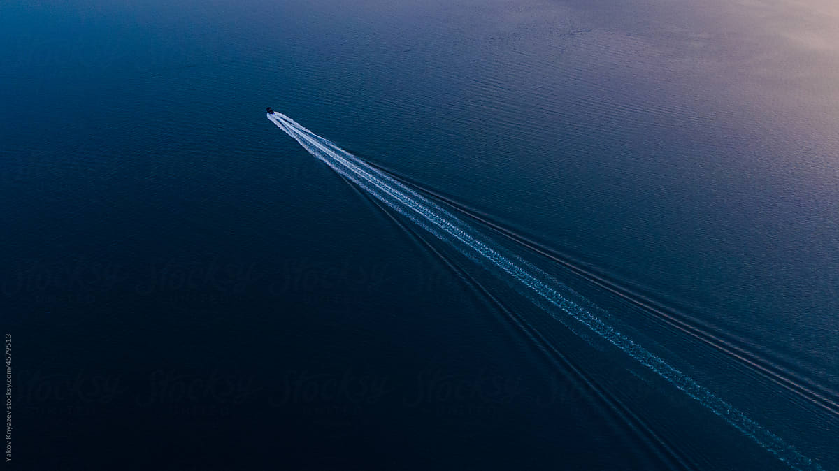 drone view of a motorboat racing fast in the sunset