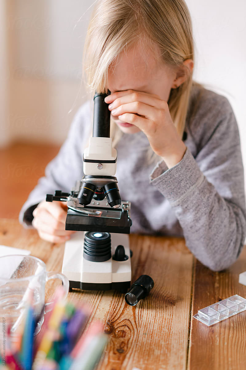 young girl looking through microscope