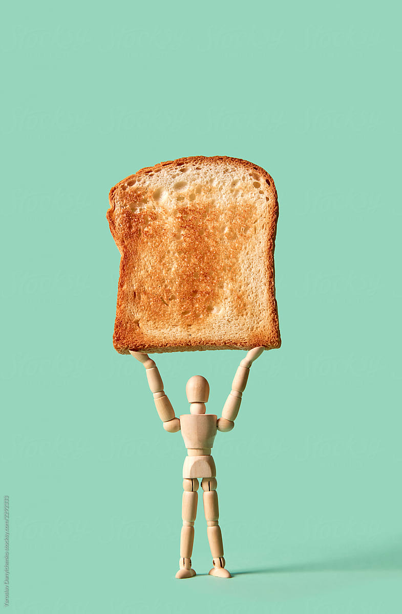 Miniature articulation mannequin holds fresh toast in his hand on a green background, copy space.