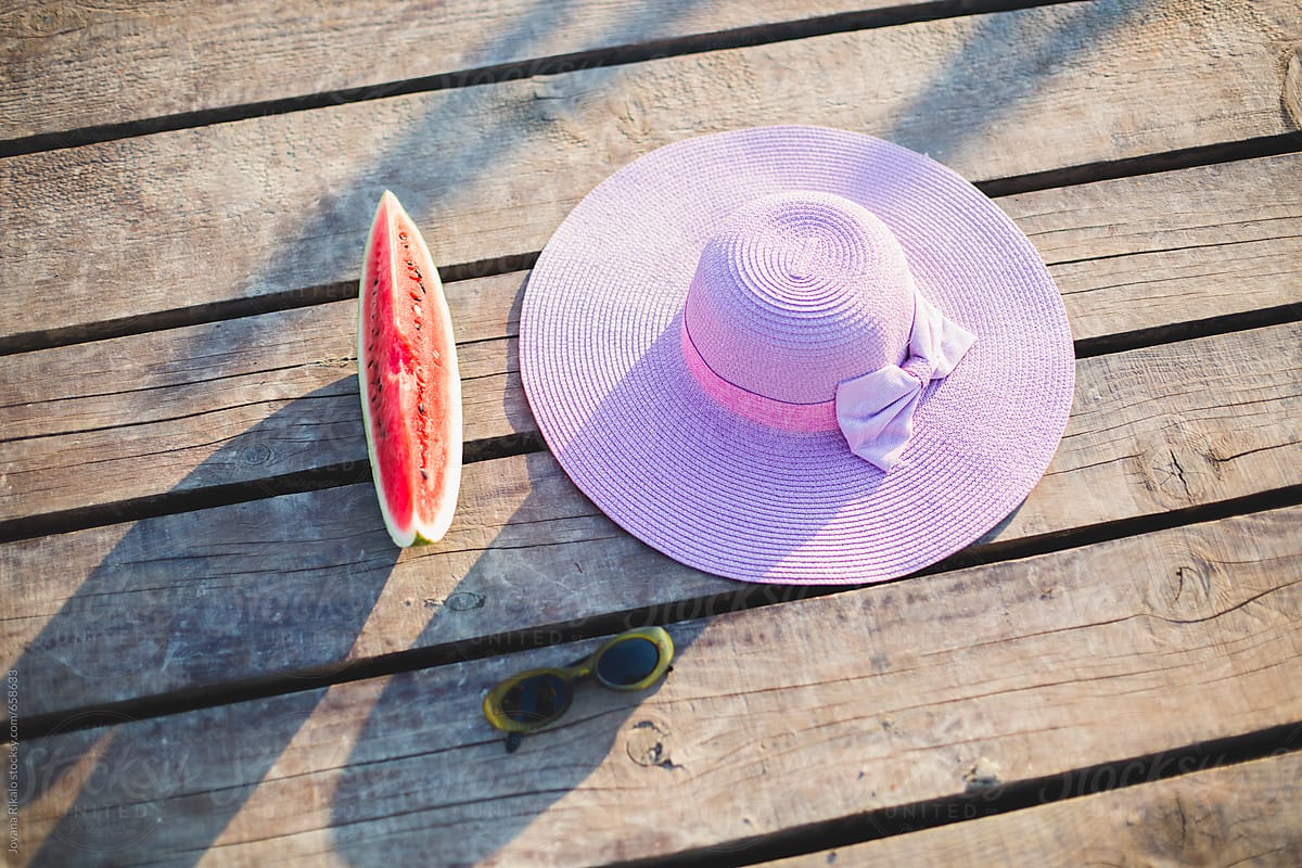 Watermelon, sunglasses and a hat on a dock