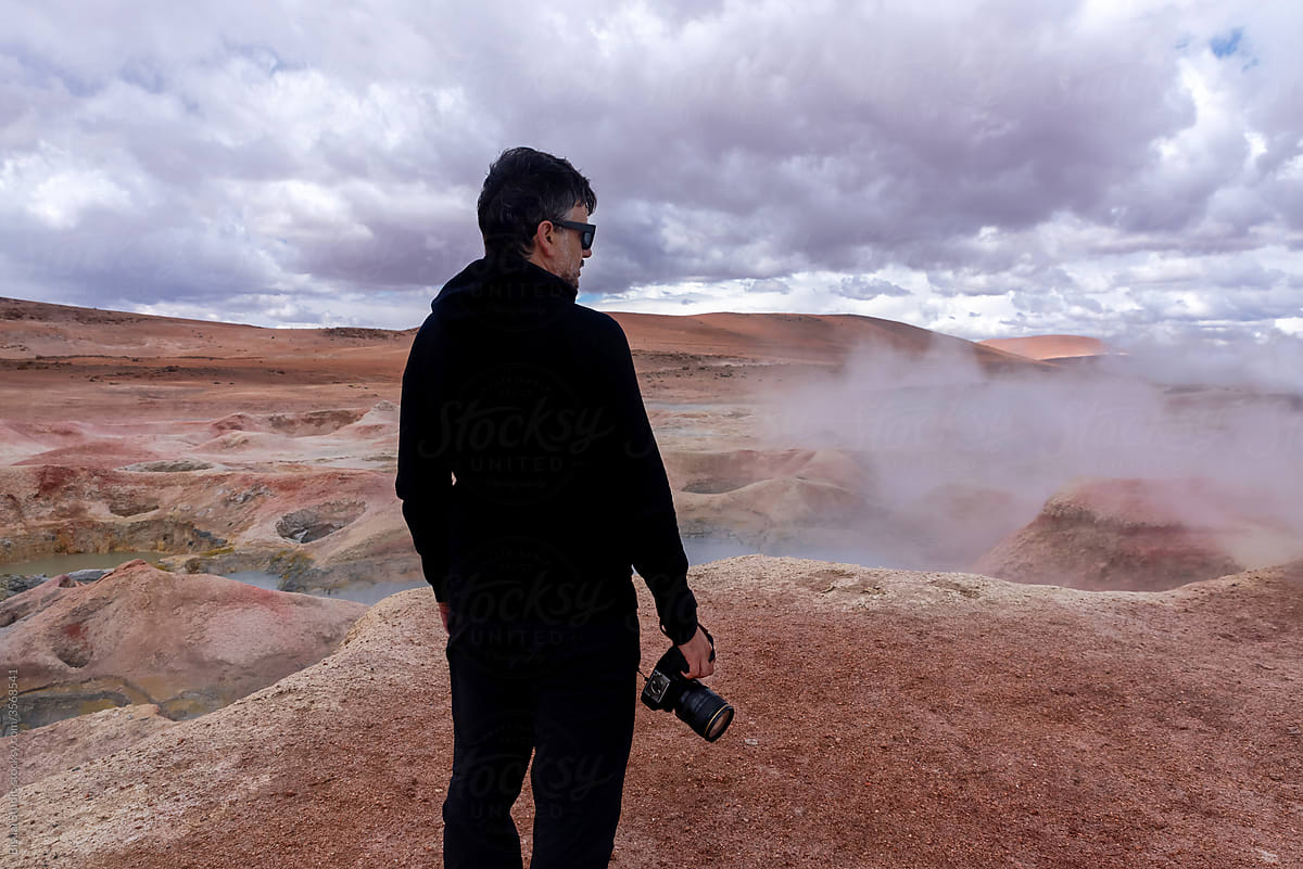 Photographer in front of some geysers with volcanic activity and mud pits