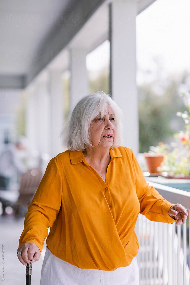 Gray hair woman wearing walking stick in elderly apartment complex