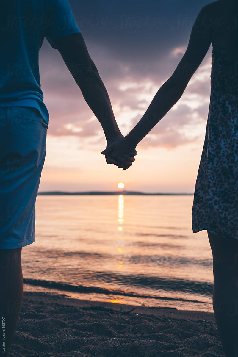 Young Couple Holding Hands On Beach On Sunset | Stocksy United