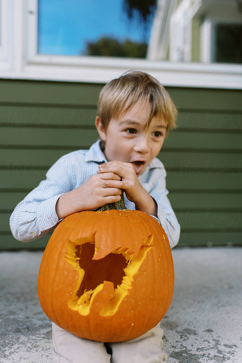 little boy holding carved pumpkin with cat motive