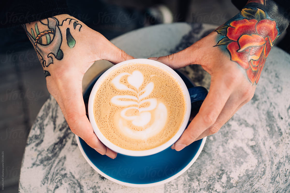 Coffee cup in hands with tattoos