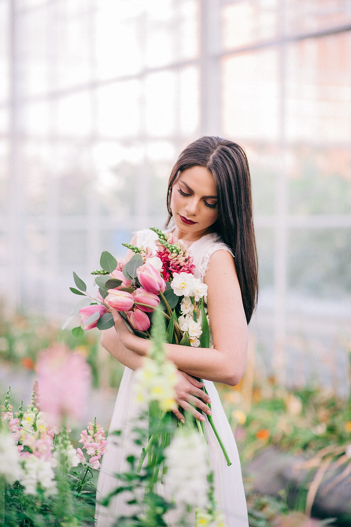 Young woman in a white dress holding flowers bouquet