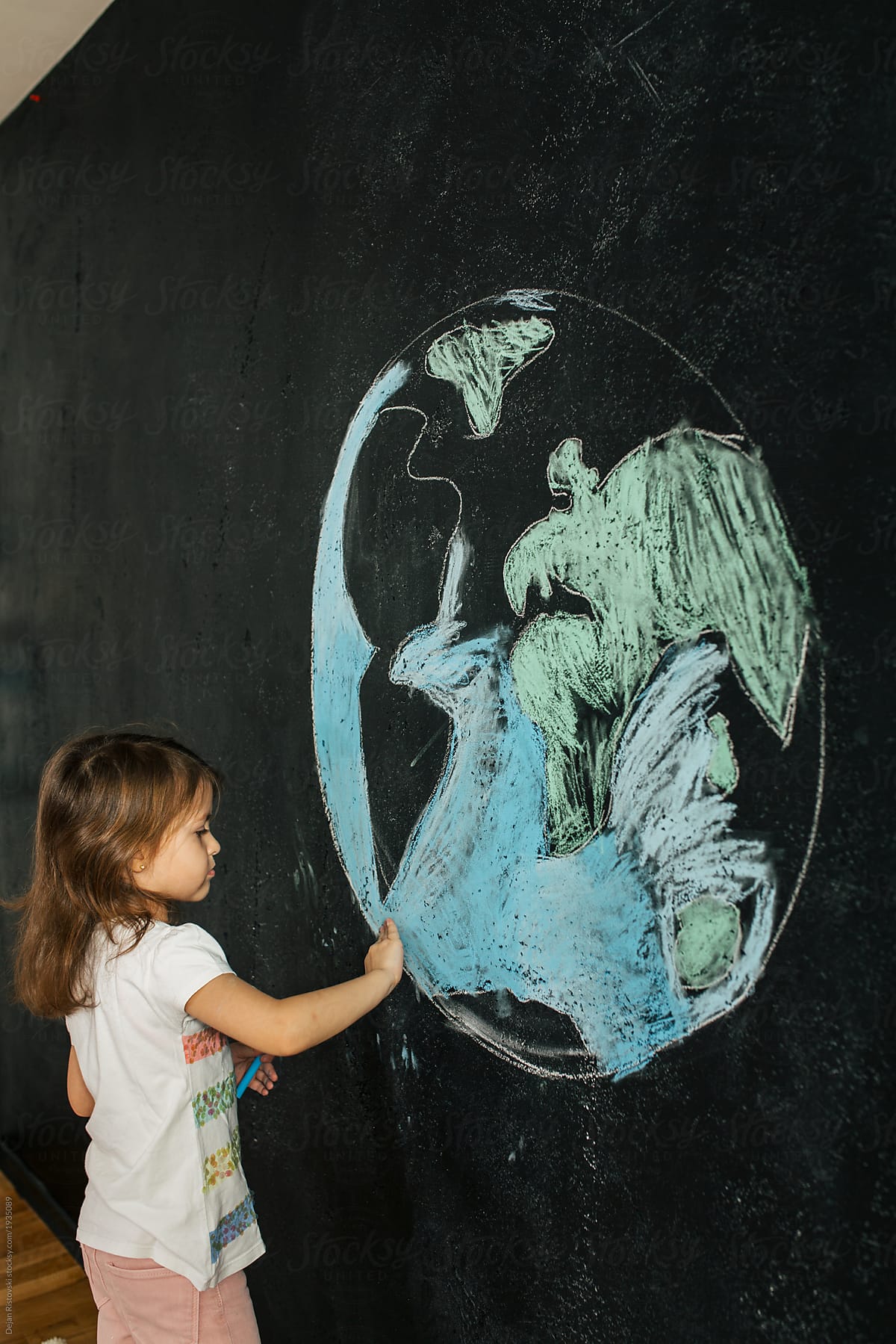 Young girl drawing planet earth on a blackboard