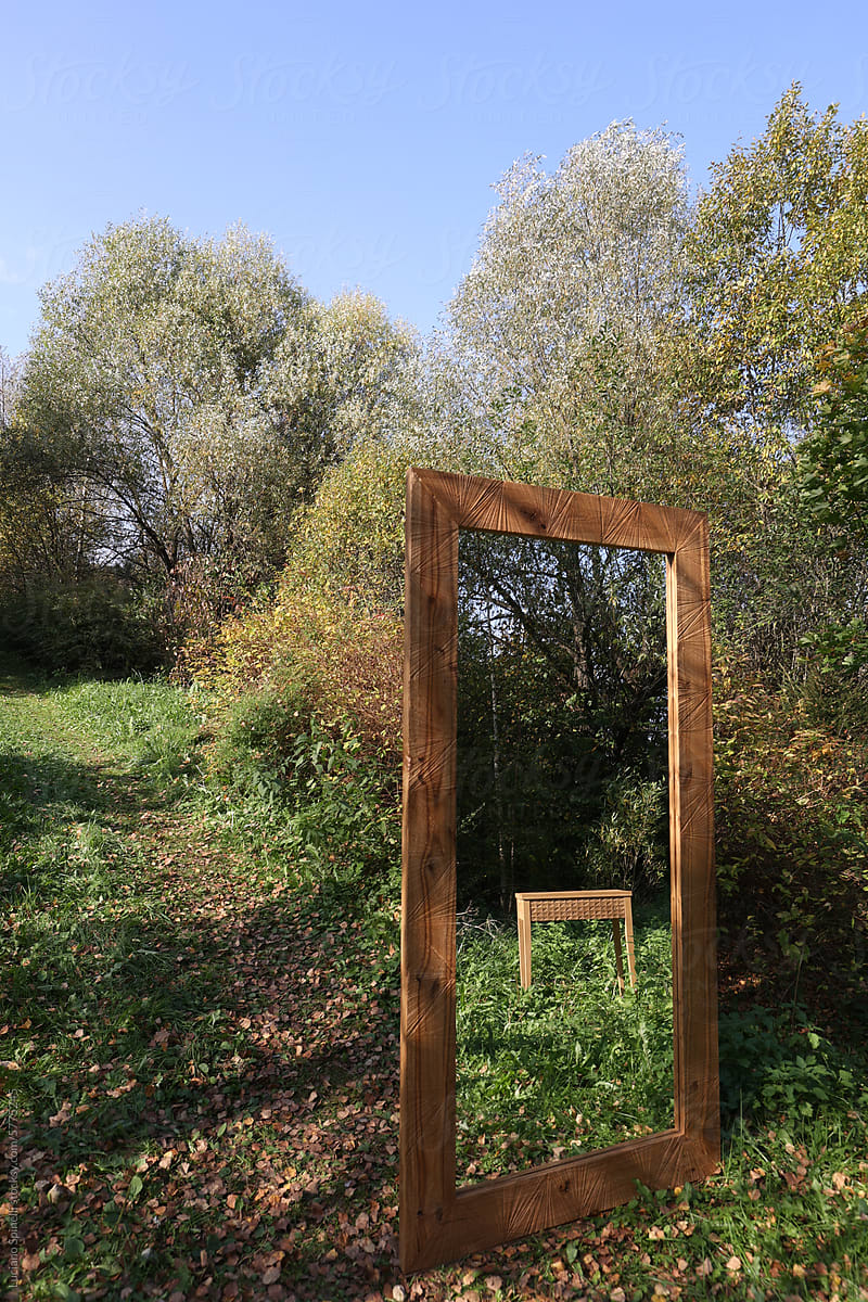 Mirror among trees reflecting handmade wood furniture in the forest