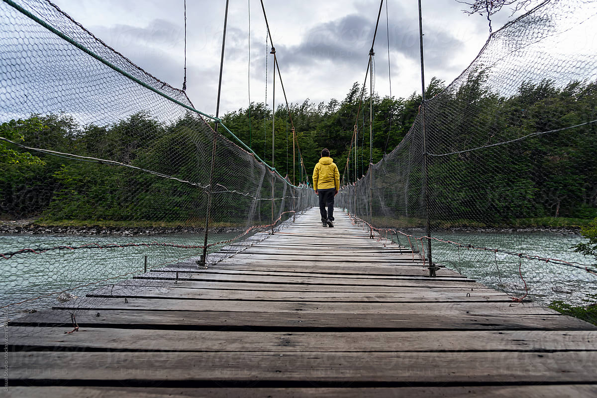 A mountaineer walking over a wooden hanging bridge
