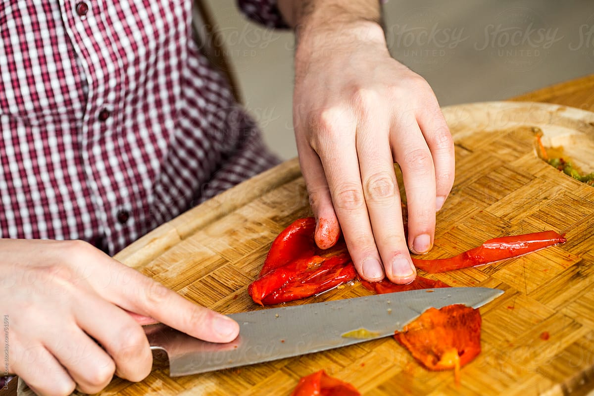 Man’s hands cutting skin off roasted peppers