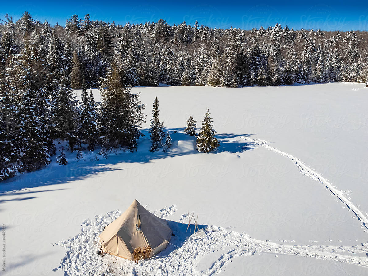 Canvas Tent on Frozen Lake with Wilderness Snowy Forest