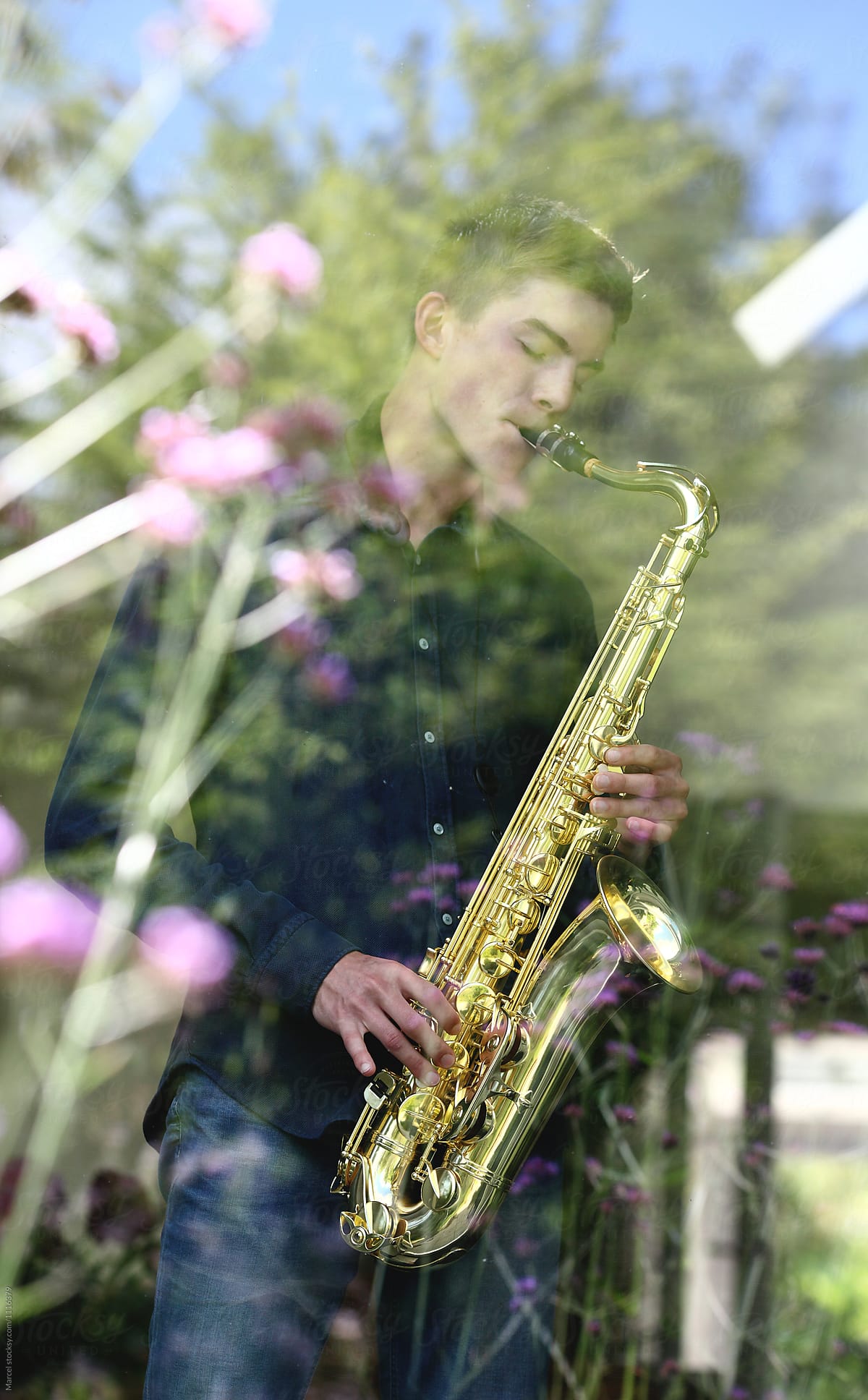 Young man playing sax behind a window