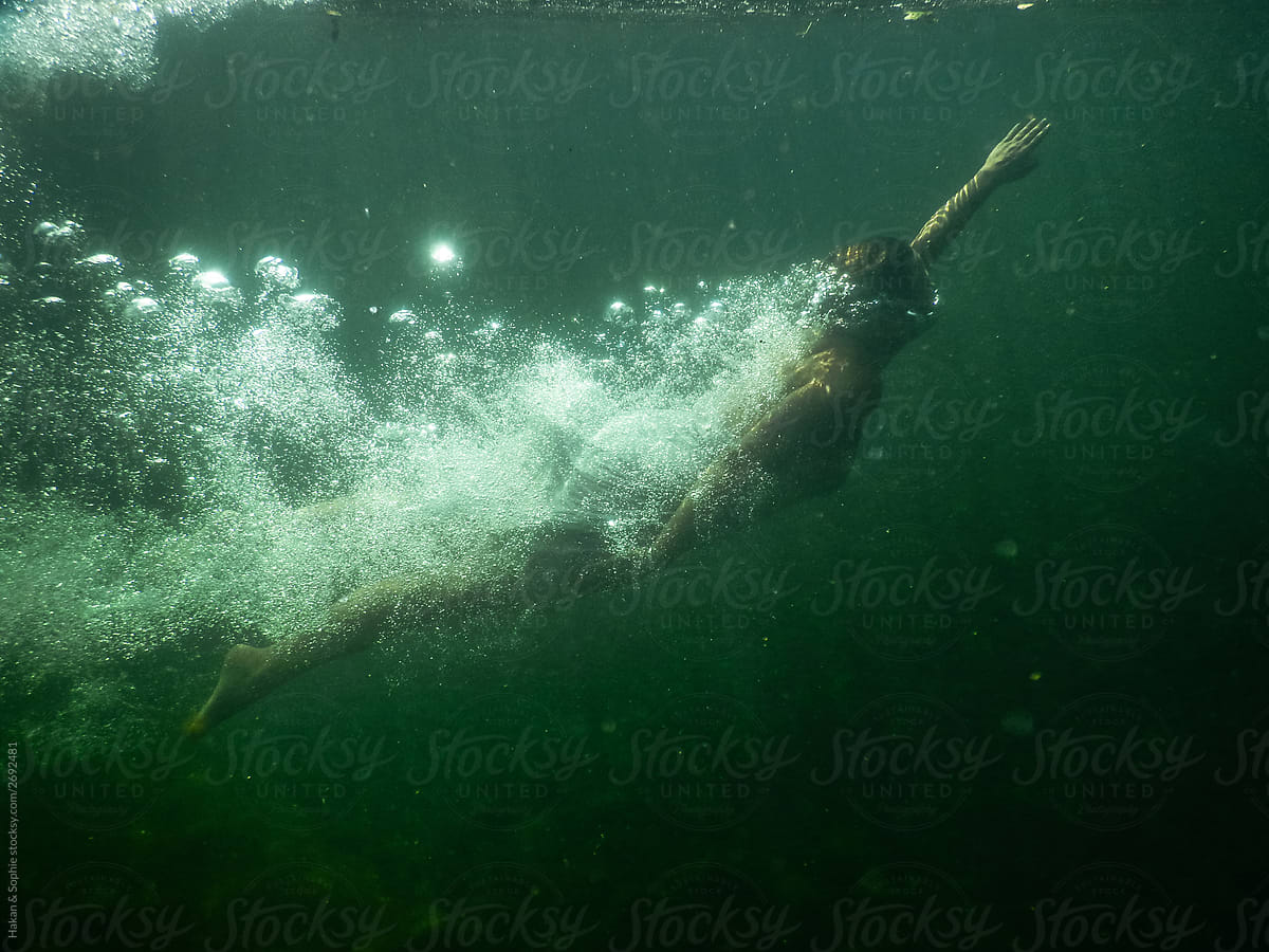 Woman covered in air bubbles swims in dark lake